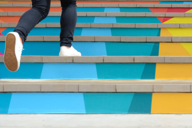 Lower part of teenage girl in casual shoe walking up outdoor colorful stair,teenage lifestyle successful concept